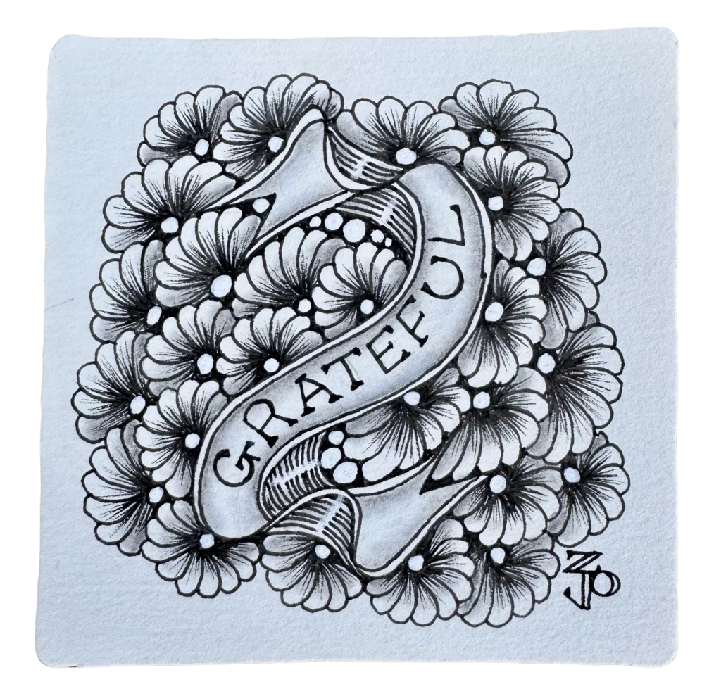 Zentangle art tile displaying the word Grateful on a curved banner, surrounded by a dense background of detailed, shaded flowers.